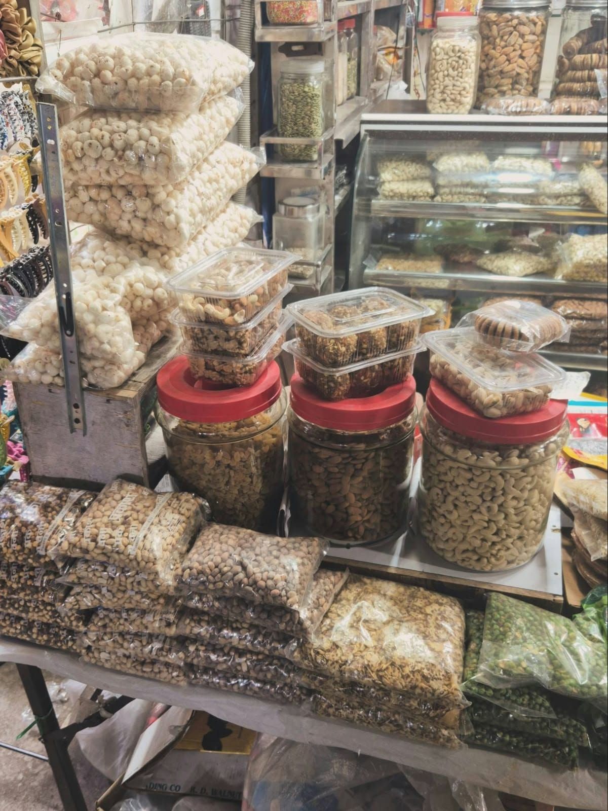 A market stall with bags full of makhana, big jars of cashews and almonds, tubs of nuts and bags of salted peas