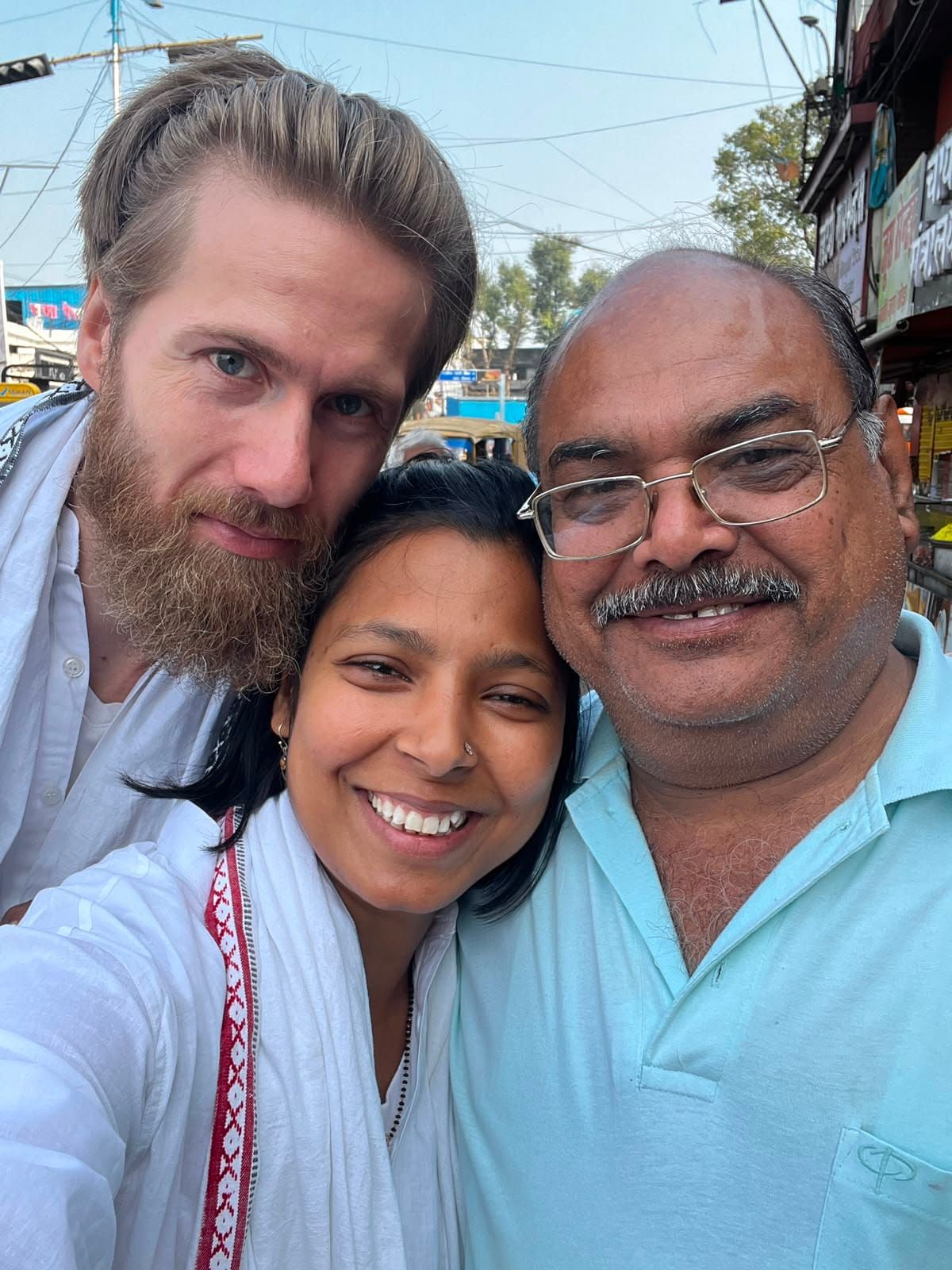 Selfie of Diederik, Yasha and a smiling older man with glasses in a light blue shirt, out on the street