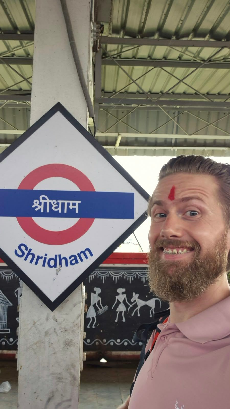 Diederik with a tilak on his forehead next to the Shridham station sign